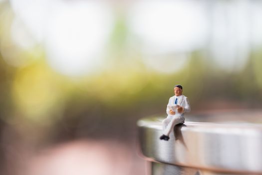 Miniature people: Businessman sitting  reading book outdoor  , Education or business concept.