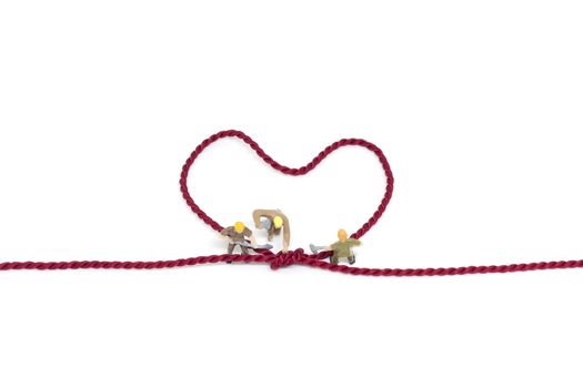 Miniature worker team building Heart Shaped with rope on white background