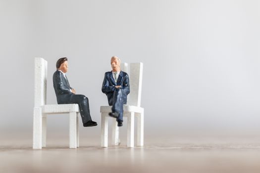 Miniature people : Businessman sitting on a chair  with copy space on white background