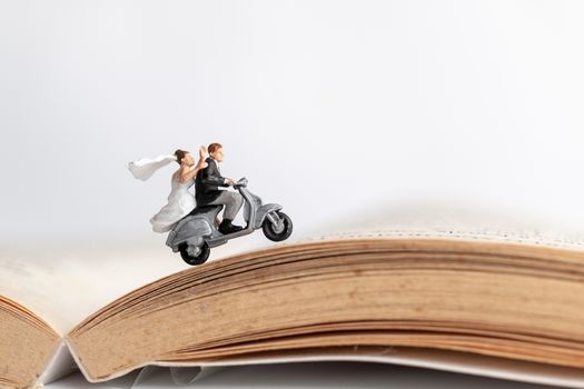 Miniature people : Couple riding the motorcycle on old book  , Valentine's Day concept