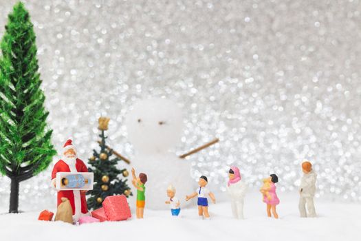Miniature people: Santa Claus and kids with snow background . Christmas and Happy New Year concept.