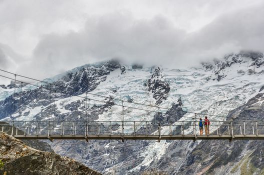 Hooker Valley Track hiking trail, New Zealand. Second swing bridge crossing the river on the Hooker Valley track, Aoraki, Mt Cook National Park with snow capped mountains landscape.