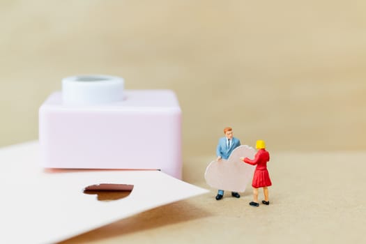 Miniature people : Couple with  paper heart on wooden  background , Valentine's Day concept
