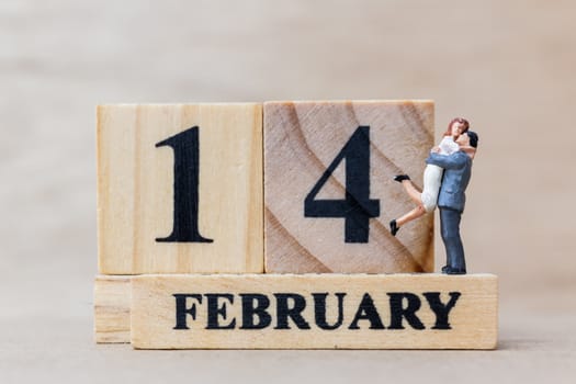 Miniature people couple with wooden block 14 FEB on wooden background, happy valentines day concept