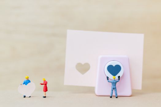 Miniature people : Couple with  paper heart on wooden  background , Valentine's Day concept