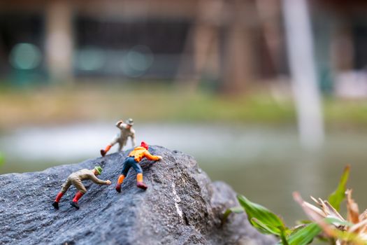 Miniature people: Hikers climbing up on the rock . Sport and leisure concept