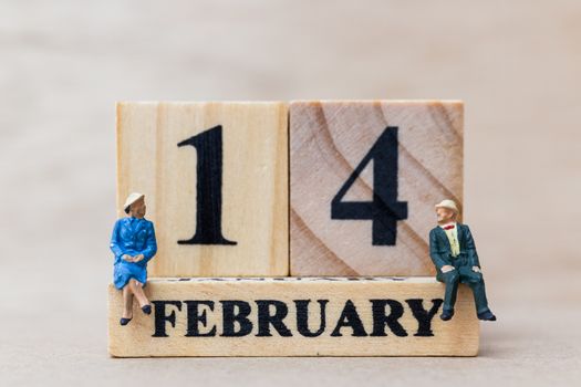 Miniature people couple with wooden block 14 FEB on wooden background, happy valentines day concept