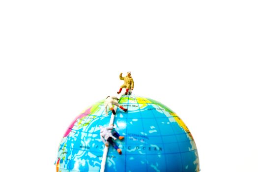 Miniature people: Hikers climbing up on the Globe . Sport and leisure concept.