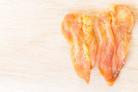 Dried chicken jerky for dogs on wooden background