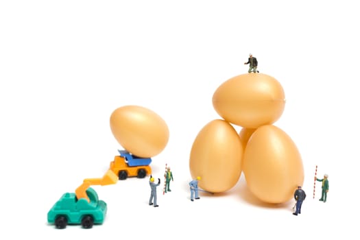 Miniature people work at Easter-eggs for Easter day on white background