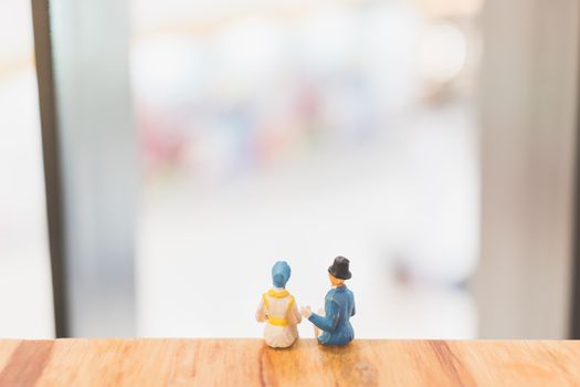 Miniature people : Couple sitting on bridge , Valentine day's concept