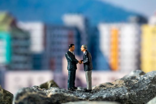 Miniature people , Businessman standing on The rock with building background