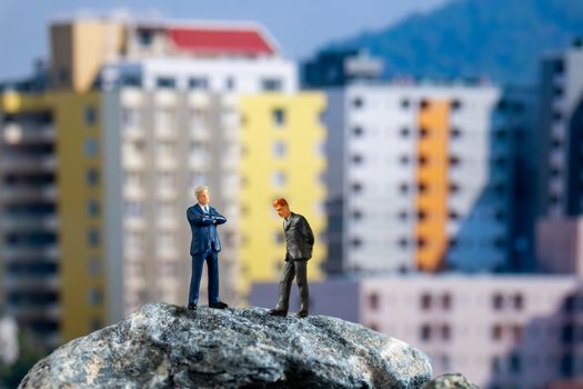 Miniature people , Businessman standing on The rock with building background
