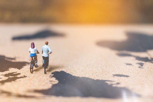 Miniature people travelers riding bicycle on world map , Traveling and exploring the world Concept