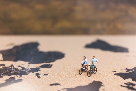 Miniature people travelers riding bicycle on world map , Traveling and exploring the world Concept