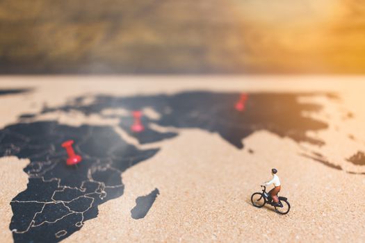 Miniature people travelers riding bicycle on world map , Traveling and exploring the world Concept