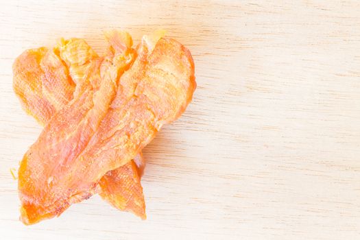 Dried chicken jerky for dogs on wooden background