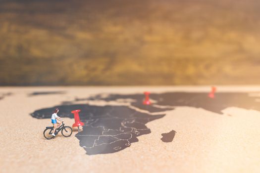 Miniature people travelers riding bicycle on world map , Traveling and exploring the world Concept