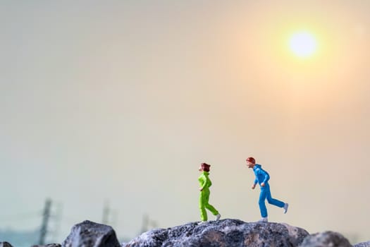 Miniature people : Running on rock cliff with nature background , Health And lifestyle concepts