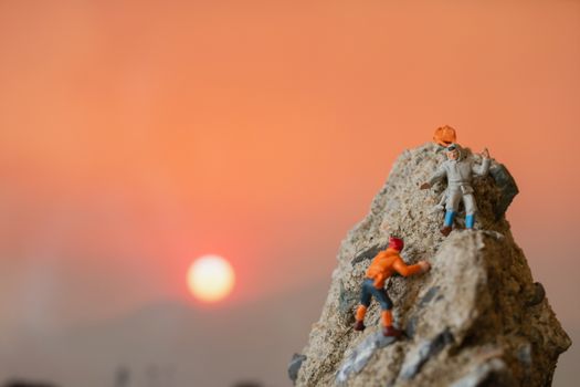 Miniature people: Hikers climbing up on the rock . Sport and leisure concept.