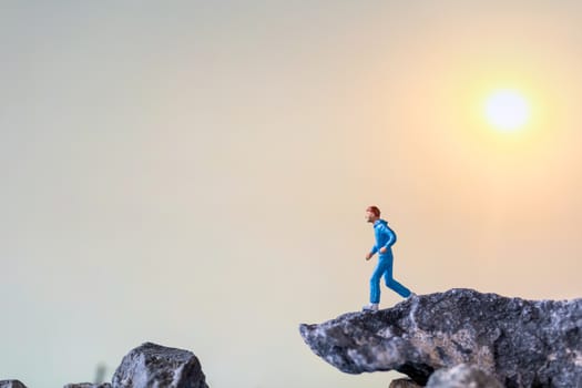 Miniature people : Running on rock cliff with nature background , Health And lifestyle concepts