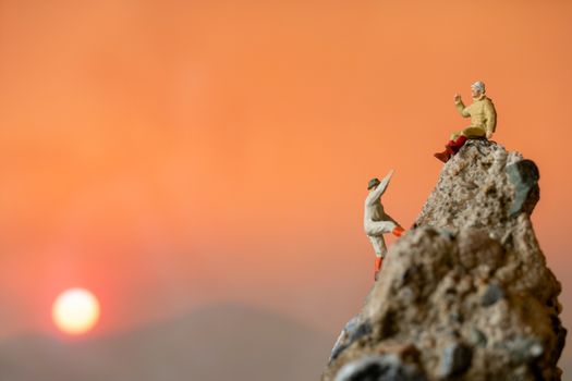 Miniature people: Hikers climbing up on the rock . Sport and leisure concept.