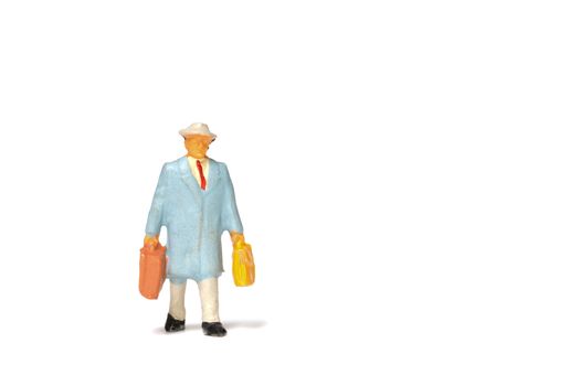 Miniature people ; Traveler holding a handbag standing on white background , Travel concept