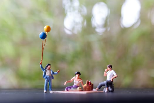 Miniature people : Happy family sitting on the mat during a picnic in a park