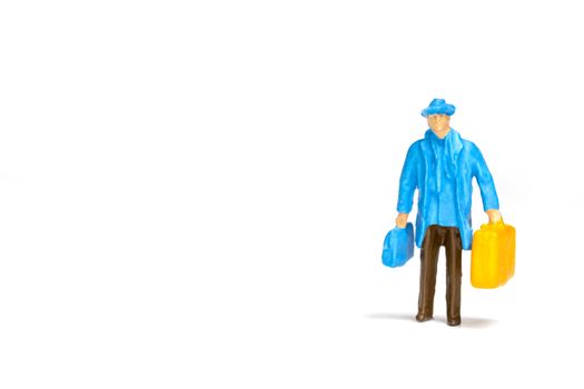 Miniature people ; Traveler holding a handbag standing on white background , Travel concept
