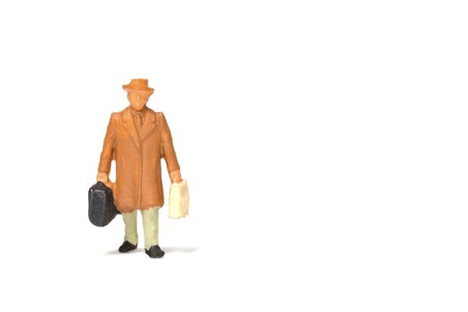 Miniature people ; Traveler holding a handbag standing on white background , Travel concept