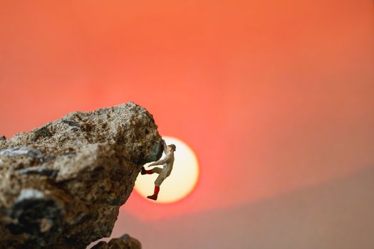 Miniature people: Hikers climbing up on the rock . Sport and leisure concept.