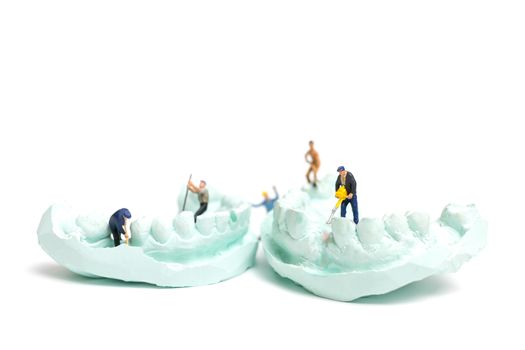 Miniature Worker team is filing fake teeth and placing them in a denture made with plaster. Dental prosthesis laboratory.