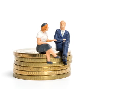 Miniature people: Businessman sitting on stack of coin , Money and financial concepts.