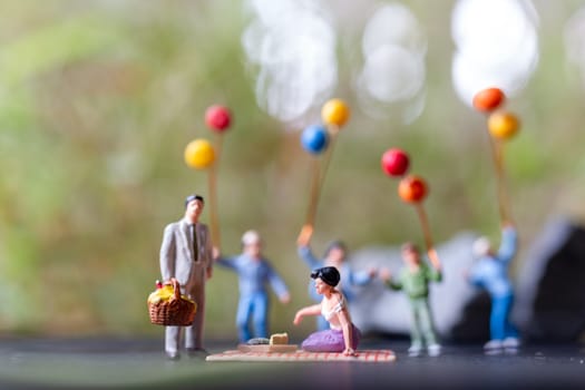Miniature people : Happy family sitting on the mat during a picnic in a park