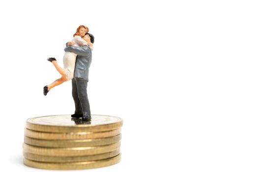 Miniature people: Couple hugging standing on stack of coin , Money and financial concepts.
