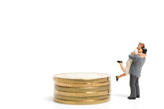 Miniature people: Couple hugging standing on stack of coin , Money and financial concepts.