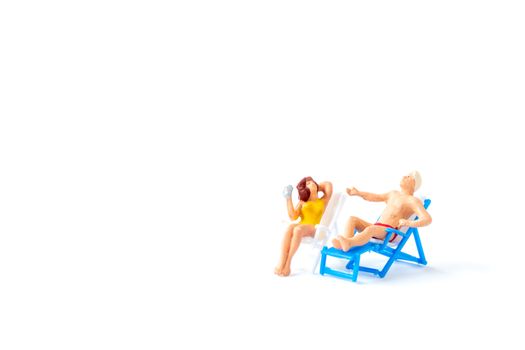 Miniature people sunbathing on deck chairs on white background , Summer time concept
