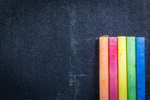 Row of rainbow colored chalk on blackboard