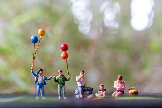 Miniature people : Happy family sitting on the mat during a picnic in a park