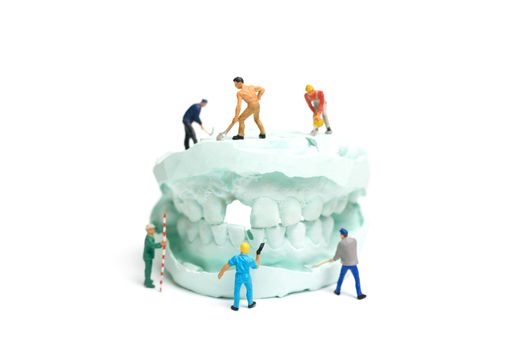 Miniature Worker team is filing fake teeth and placing them in a denture made with plaster. Dental prosthesis laboratory.