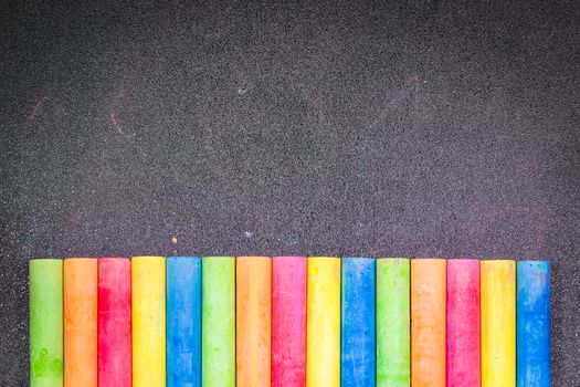 Row of rainbow colored chalk on blackboard