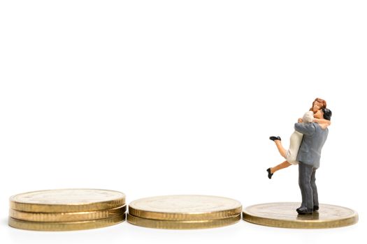 Miniature people: Couple hugging standing on stack of coin , Money and financial concepts.