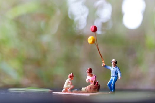 Miniature people : Happy family sitting on the mat during a picnic in a park