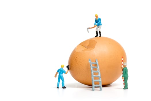 Miniature people work at Easter-eggs for Easter day on white background