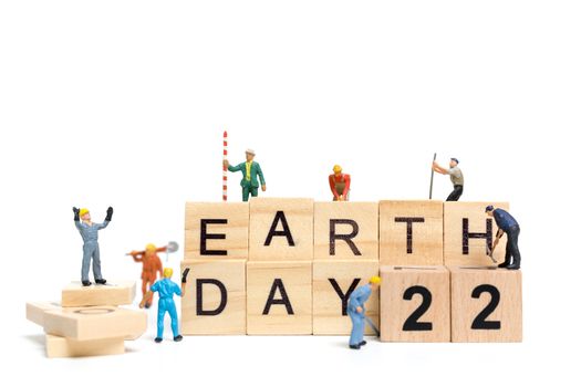 Miniature people : Worker team building word " Earth day " on wooden block with wooden background , Earth day concept