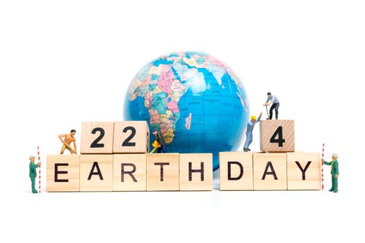 Miniature people : Worker team building word " Earth day " on wooden block with wooden background , Earth day concept