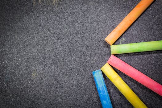 Row of rainbow colored chalk on blackboard