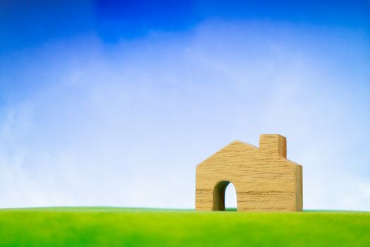 Wooden house model on green grass. Eco-friendly house concept.