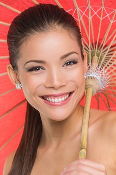 Asian model in studio smiling with paper umbrella sun parasol, Chinese girl smiling, multiracial beauty.