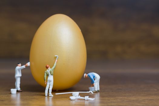 Miniature people :Painter is painting Easter-eggs for Easter day on wooden background
